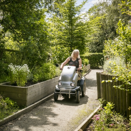 women driving scooter in garden